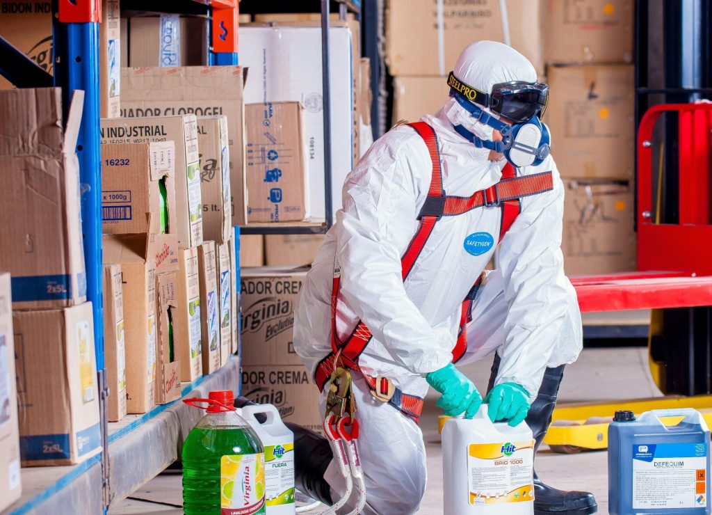 Industrial worker in protective gear handling chemicals in a warehouse environment.